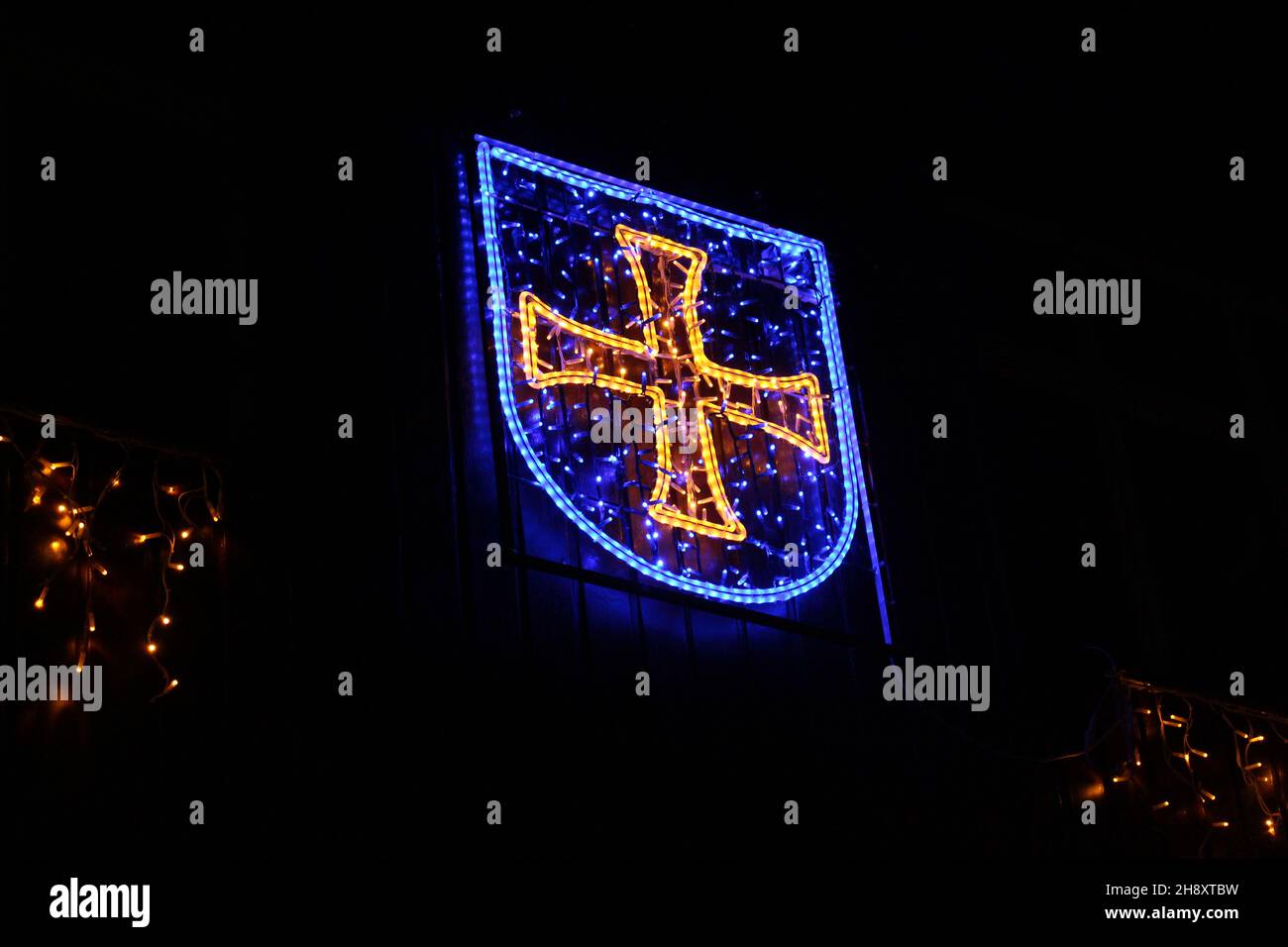 Armoiries d'Albisrieden, Zurich (croix jaune dans un bouclier bleu) illuminées par des lumières de Noël sur fond noir (Suisse) Banque D'Images