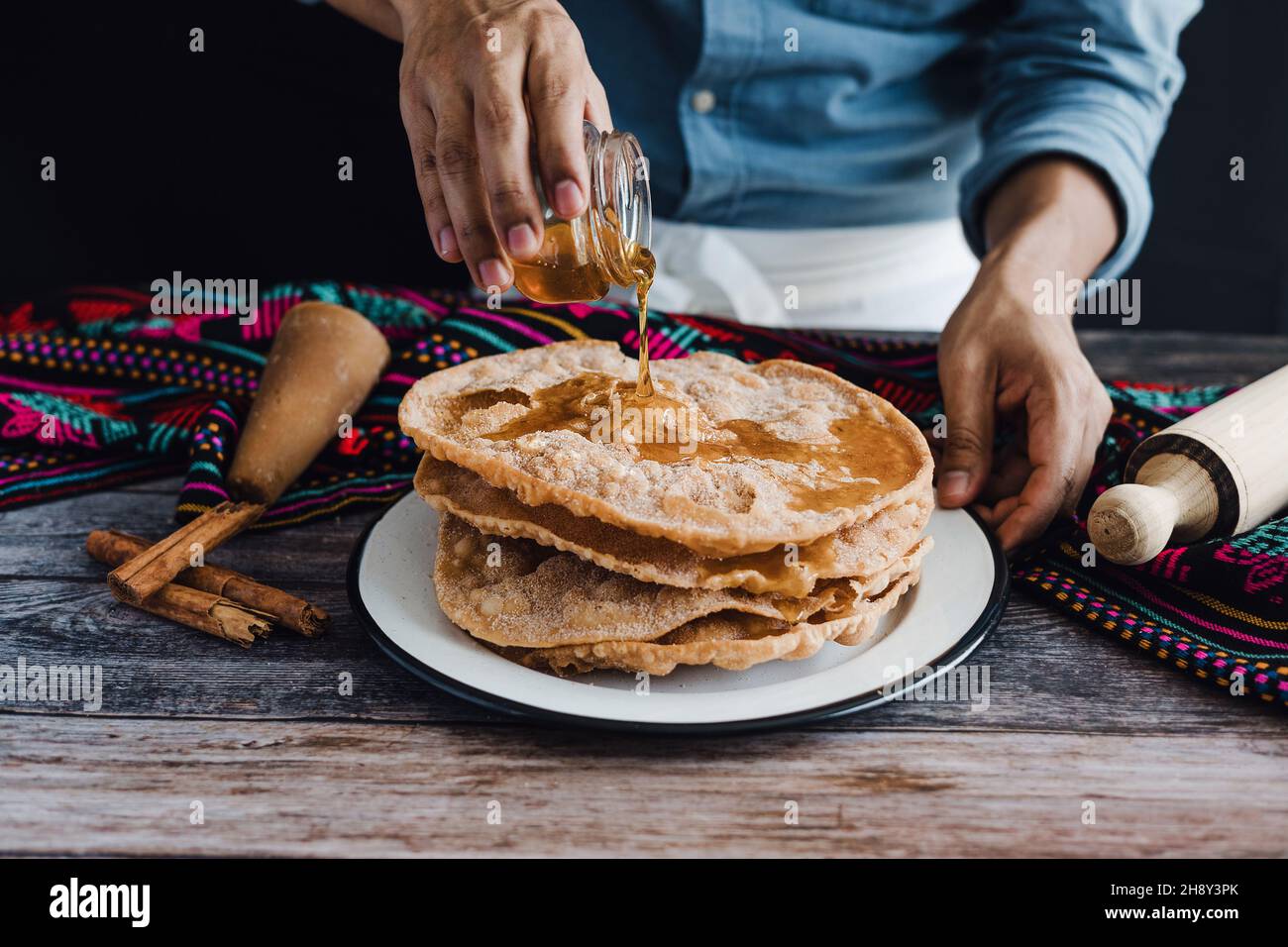 Mains de l'homme mexicain tenant un pot de miel préparant des buñuelos mexicains, recette et ingrédients du dessert traditionnel pour Noël au Mexique Banque D'Images