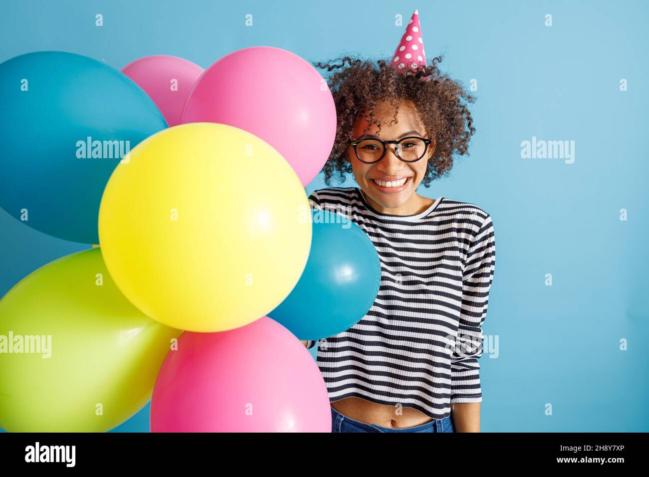 Bonne femme joyeuse avec ballons de fête debout en studio Banque D'Images