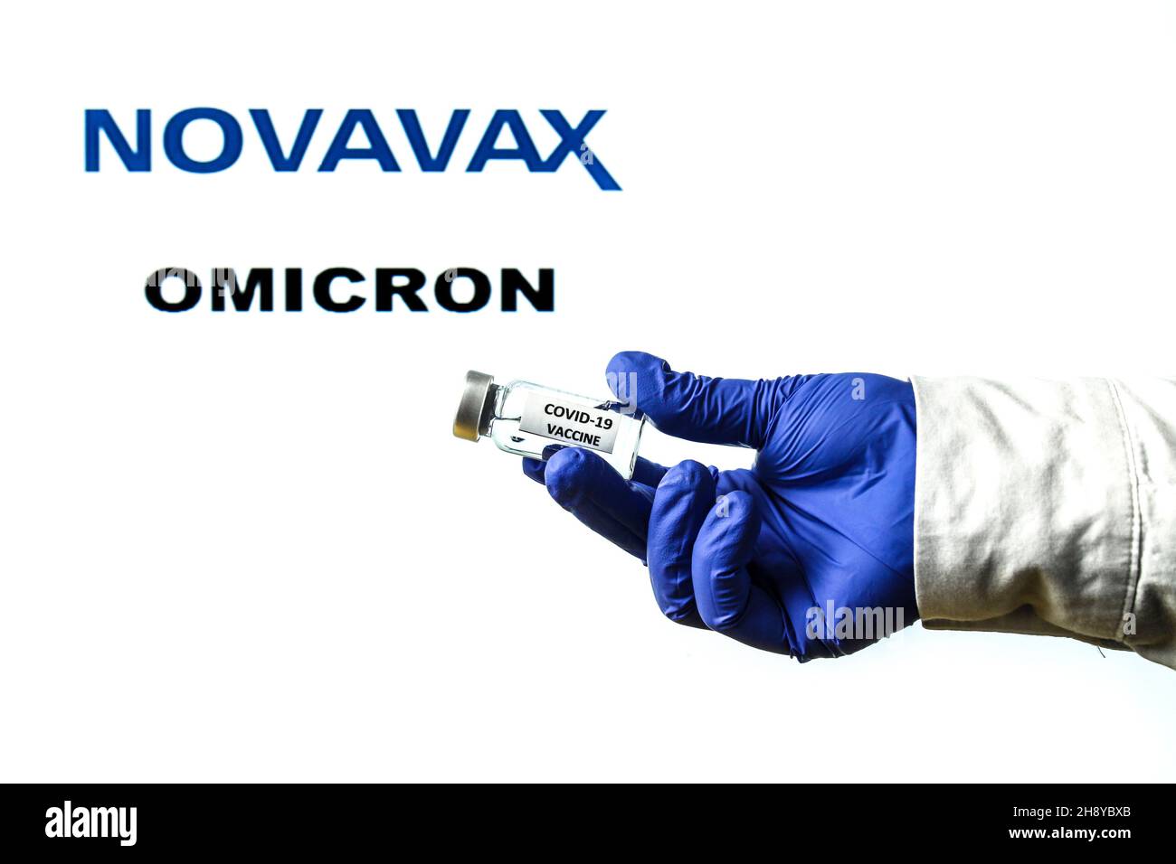 Madrid, Espagne - 29 novembre 2021 : flacon à main avec vaccin contre le covid.Logo Novavax et Omicron covid variante mot écrit en arrière-plan Banque D'Images