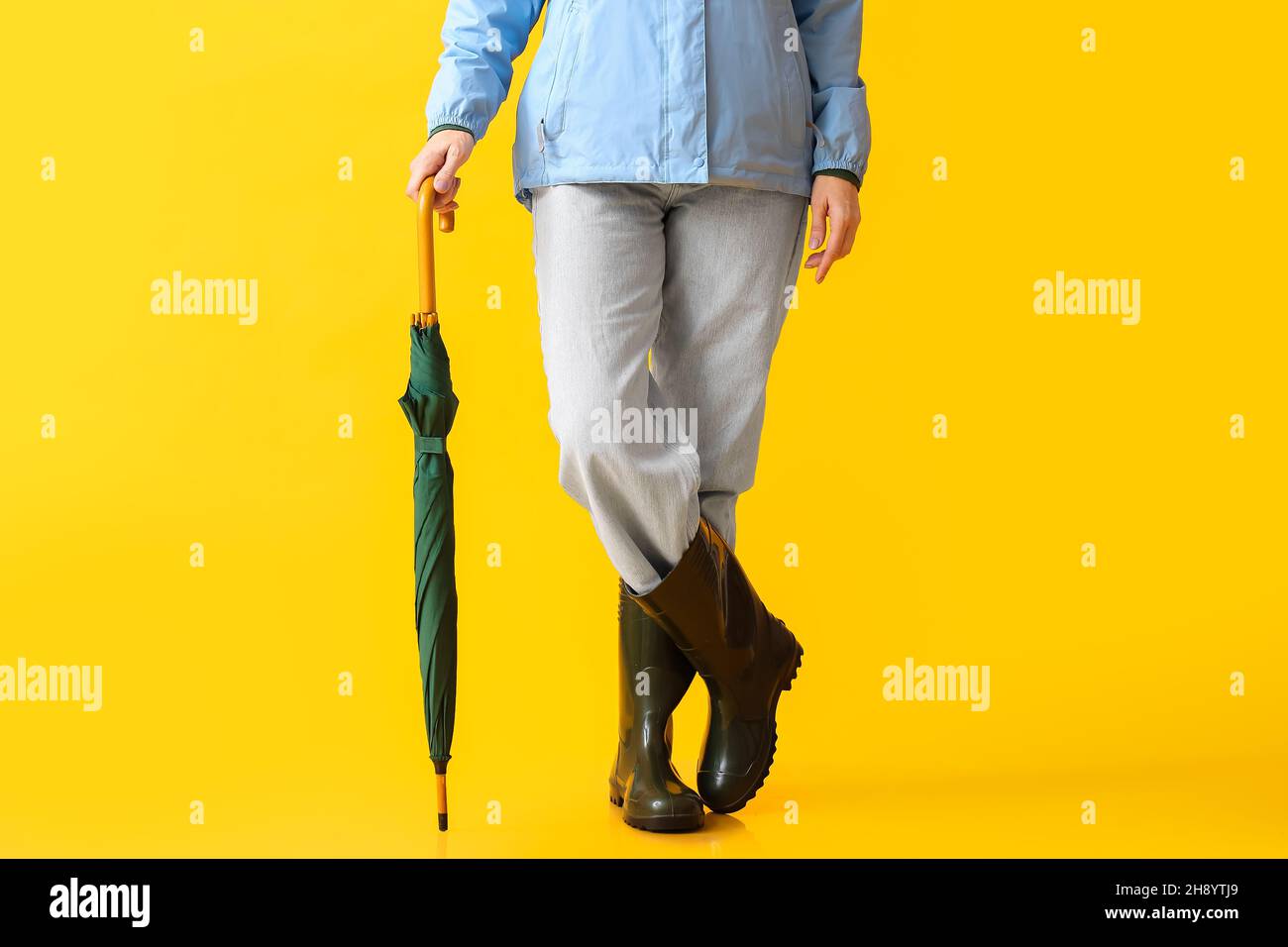 Belle femme mûre en bottes de gommer et avec parapluie sur fond de couleur  Photo Stock - Alamy