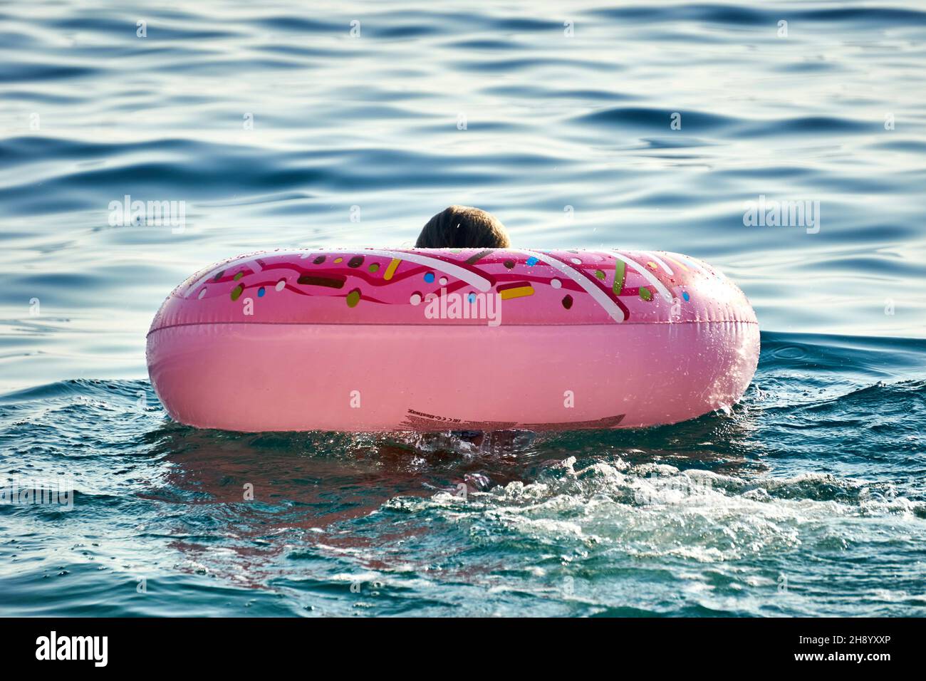 Personne avec anneau gonflable en forme de beignet nageant dans la se Banque D'Images