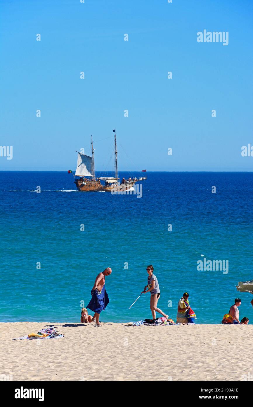 Les touristes se détendre sur la plage et à la mer avec un bateau dans la baie, Praia da Rocha, Portimao, Algarve, Portugal, Europe. Banque D'Images