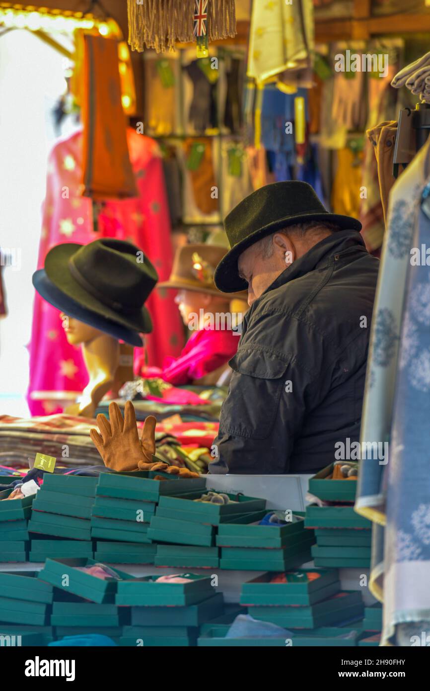 un homme plus âgé est détenteur d'une stalle sur un marché de noël à southampton et vend des chapeaux et des scroves colorés, un marchand de marché sur un marché de noël, des chapeaux de porte-stalle Banque D'Images