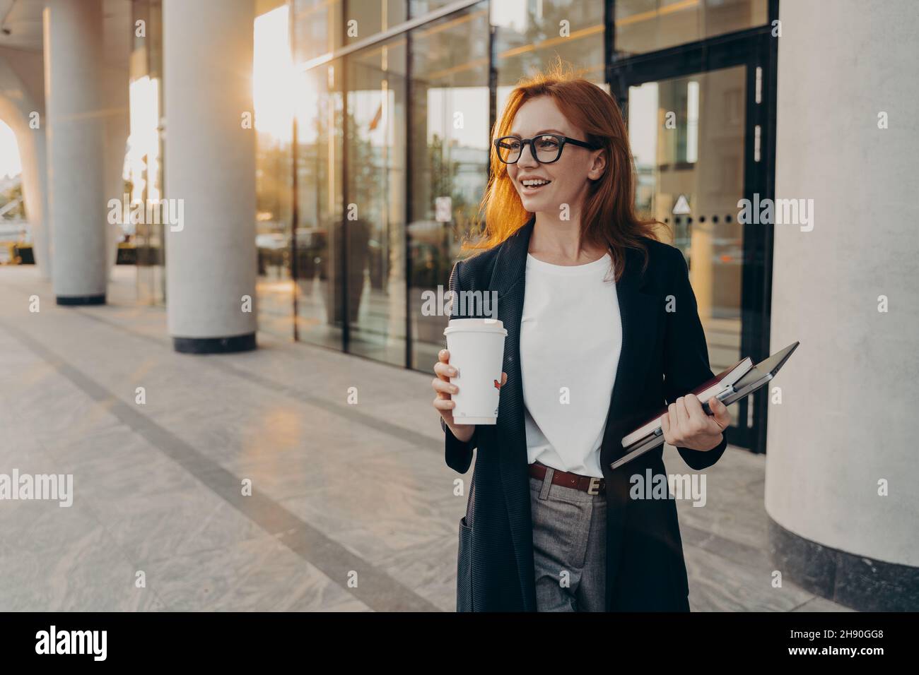 Le modèle femelle contient un bloc-notes à pavé tactile et une tasse de café à emporter en plein air par temps ensoleillé Banque D'Images