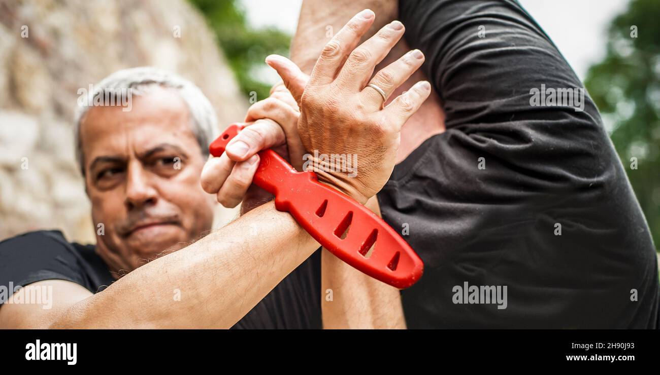 Démonstration du désarmement du couteau.Un instructeur de Kaap pratique les arts martiaux auto-défense couteau menace technique de désarmement.Formation sur la rétention et le désarmement des armes Banque D'Images