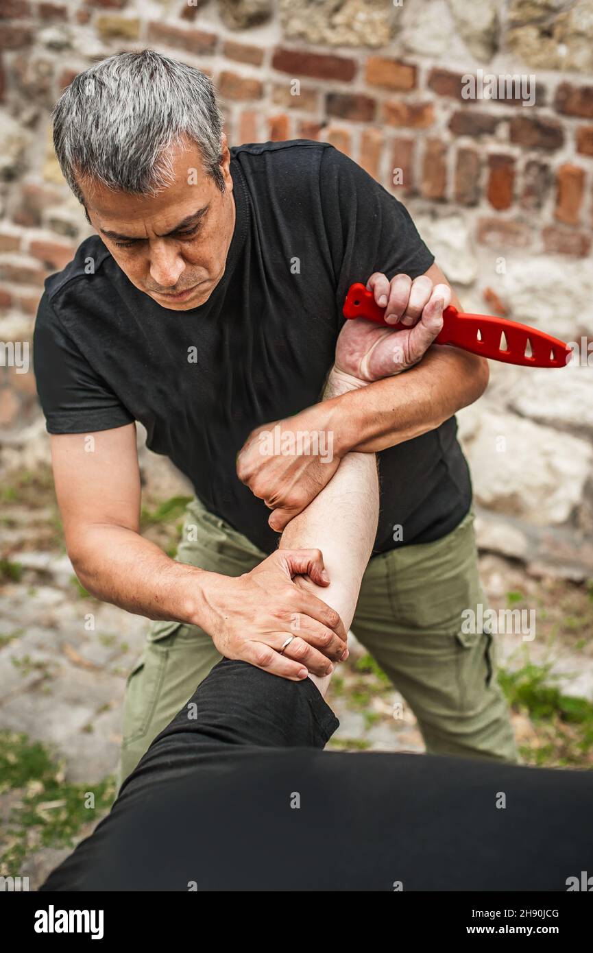 Démonstration du désarmement du couteau.Un instructeur de Kaap pratique les arts martiaux auto-défense couteau menace technique de désarmement.Formation sur la rétention et le désarmement des armes Banque D'Images