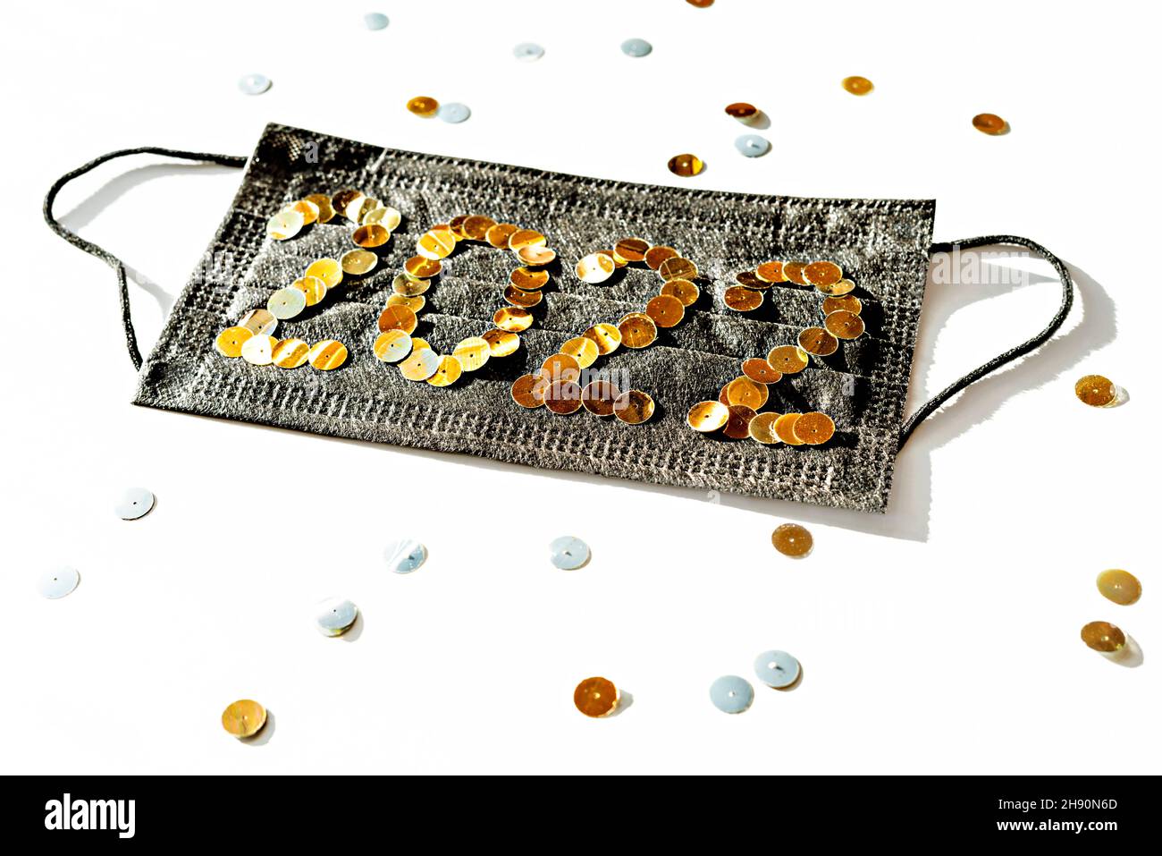 Noir médical masque de protection du visage avec le nouvel an 2022 numéros faits de paillettes dorées sur un fond blanc gros plan décorations de vacances, nouvelle réalité, Banque D'Images