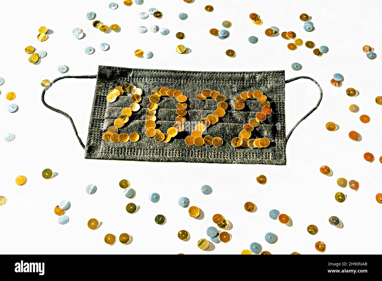 Noir médical masque de protection du visage avec le nouvel an 2022 numéros faits de paillettes dorées sur un fond blanc gros plan décorations de vacances, nouvelle réalité, Banque D'Images