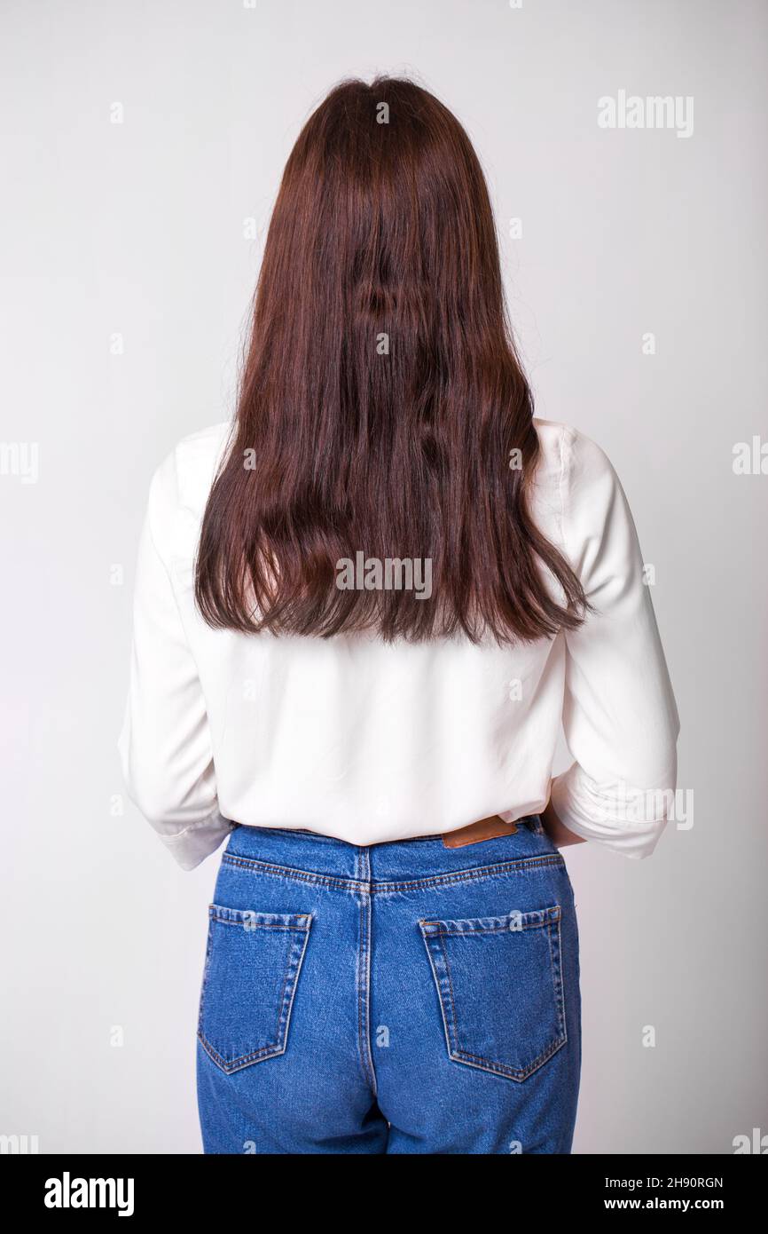 Femme long brunette cheveux, vue arrière, sur fond de mur de studio Banque D'Images