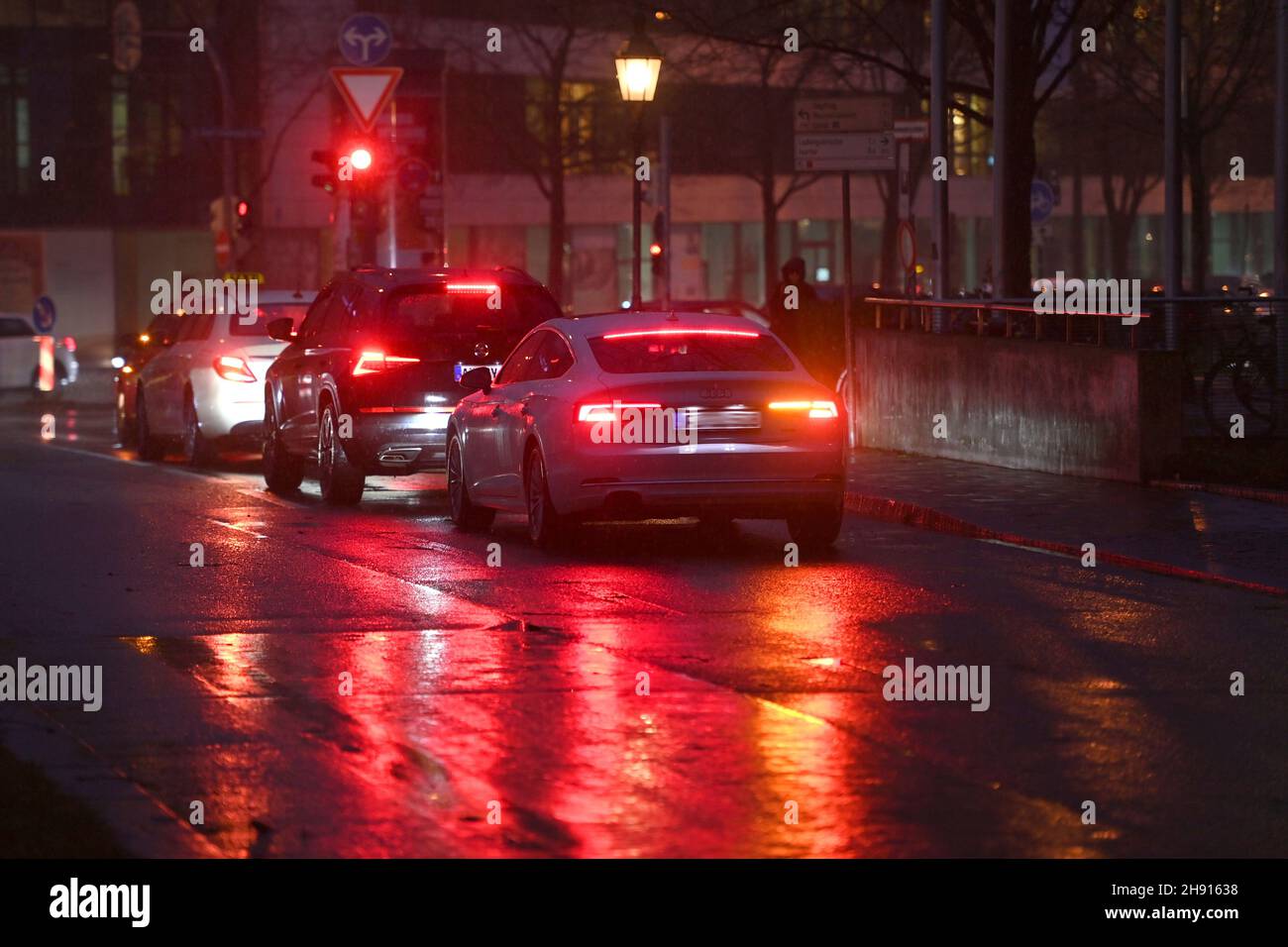 Circulation nocturne dans les rues de Munich le 2 décembre 2021.Les voitures sont garées devant un feu rouge, les feux arrière rouges réfléchit sur l'asphalte humide. Banque D'Images
