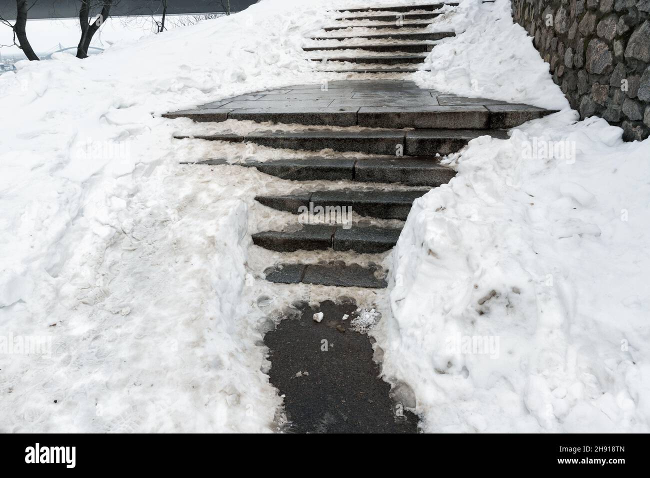Escalier en pierre de béton recouvert de neige épaisse et glissante après une tempête de neige blizzard qui s'est abattue sur la passerelle piétonne de la ville.Risque de chute Banque D'Images