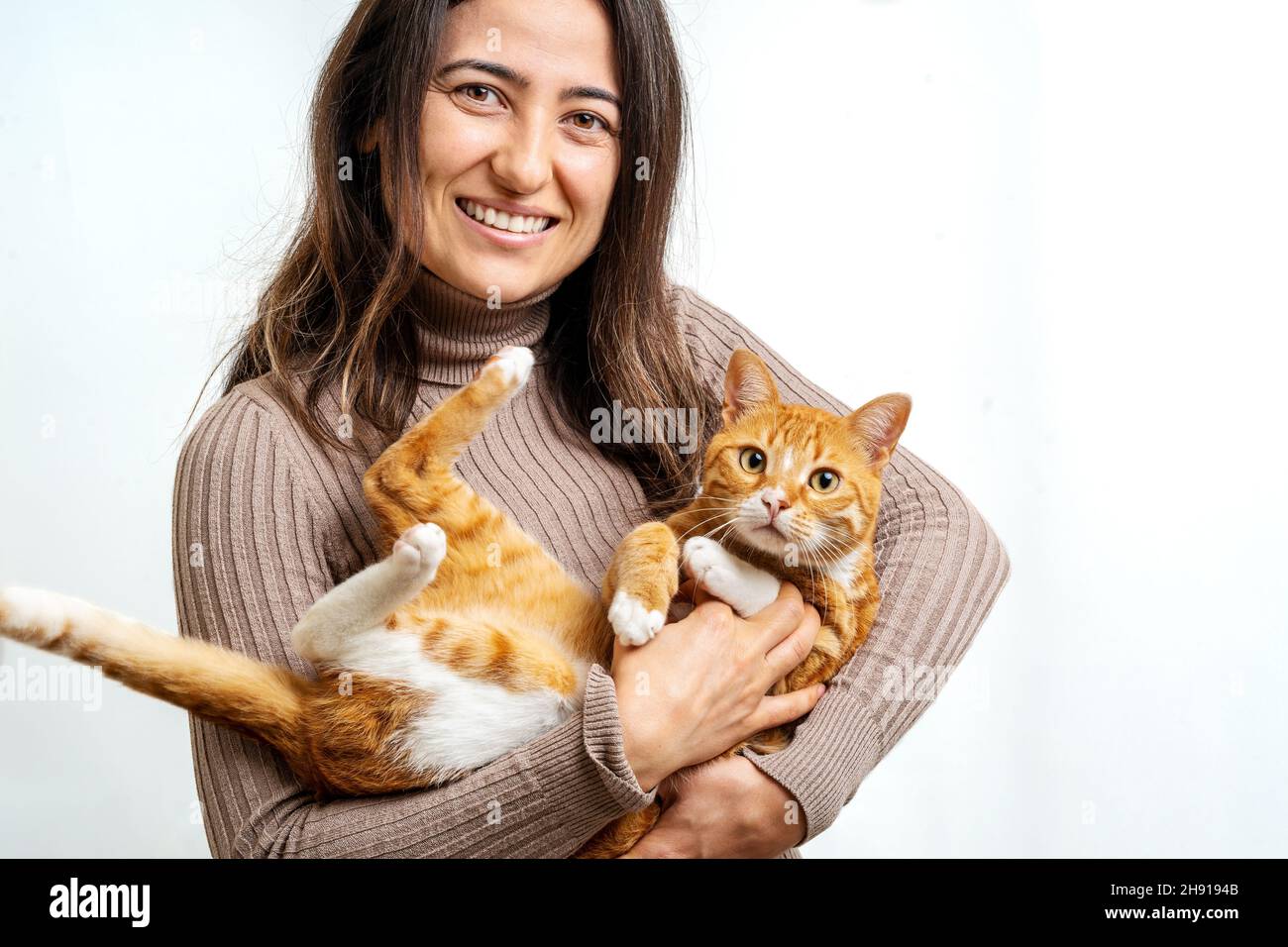 Gros plan d'une jeune femme adulte souriant avec un chat tabby domestique sur un fond isolé.Le concept de chat et d'animal de compagnie. Banque D'Images