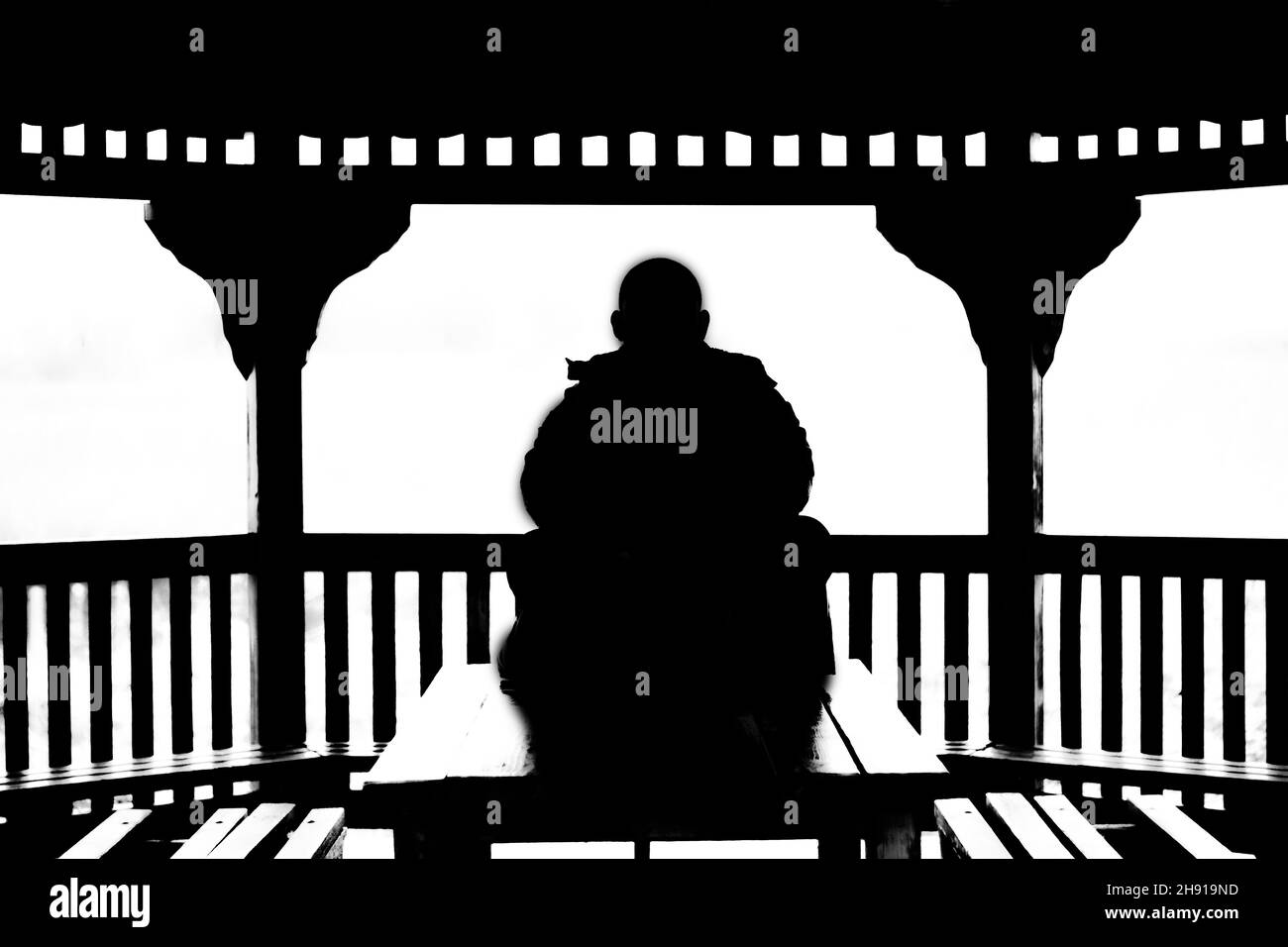Silhouette d'un homme assis sur une table sur un balcon Banque D'Images