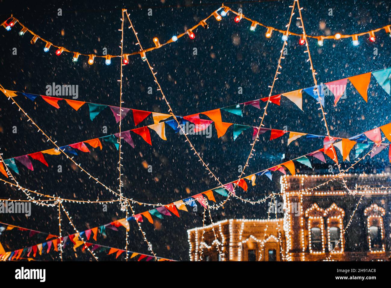 Neige volante dans la lumière du soir dans une atmosphère magique festive du nouvel an avec guirlandes et drapeaux Banque D'Images