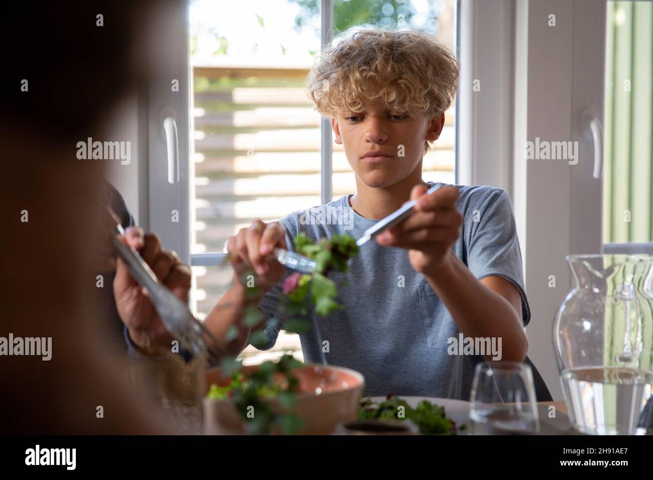 Un pré-adolescent mangeant de la nourriture dans la salle à manger à la maison Banque D'Images