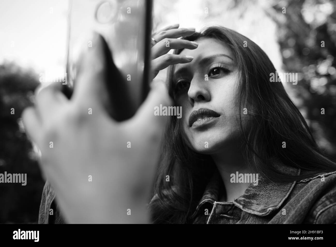 Une jolie fille qui vérifie son visage sur l'écran de son téléphone. Banque D'Images