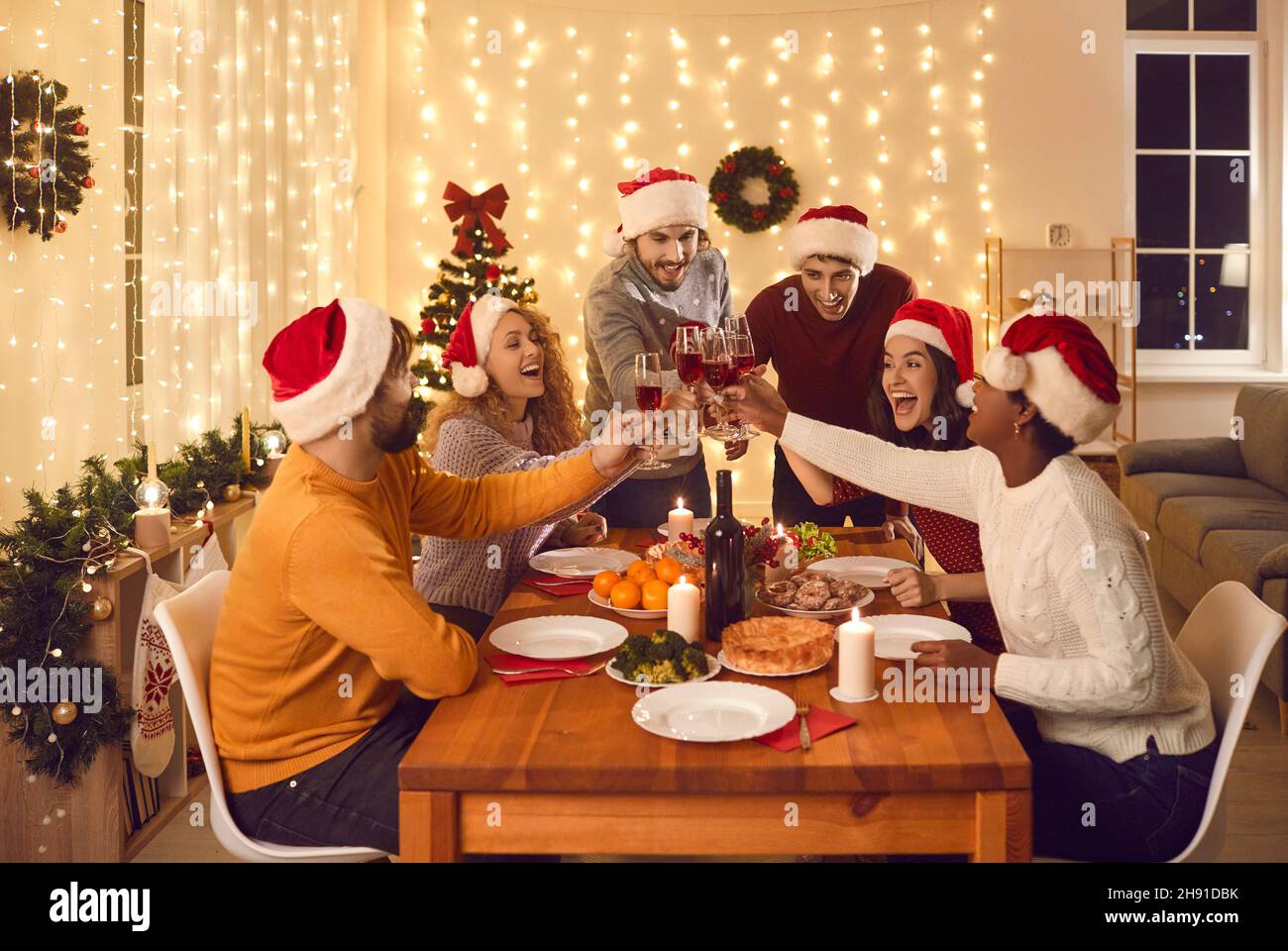 Des amis multiraciaux heureux salueront à table pour célébrer Noël Banque D'Images