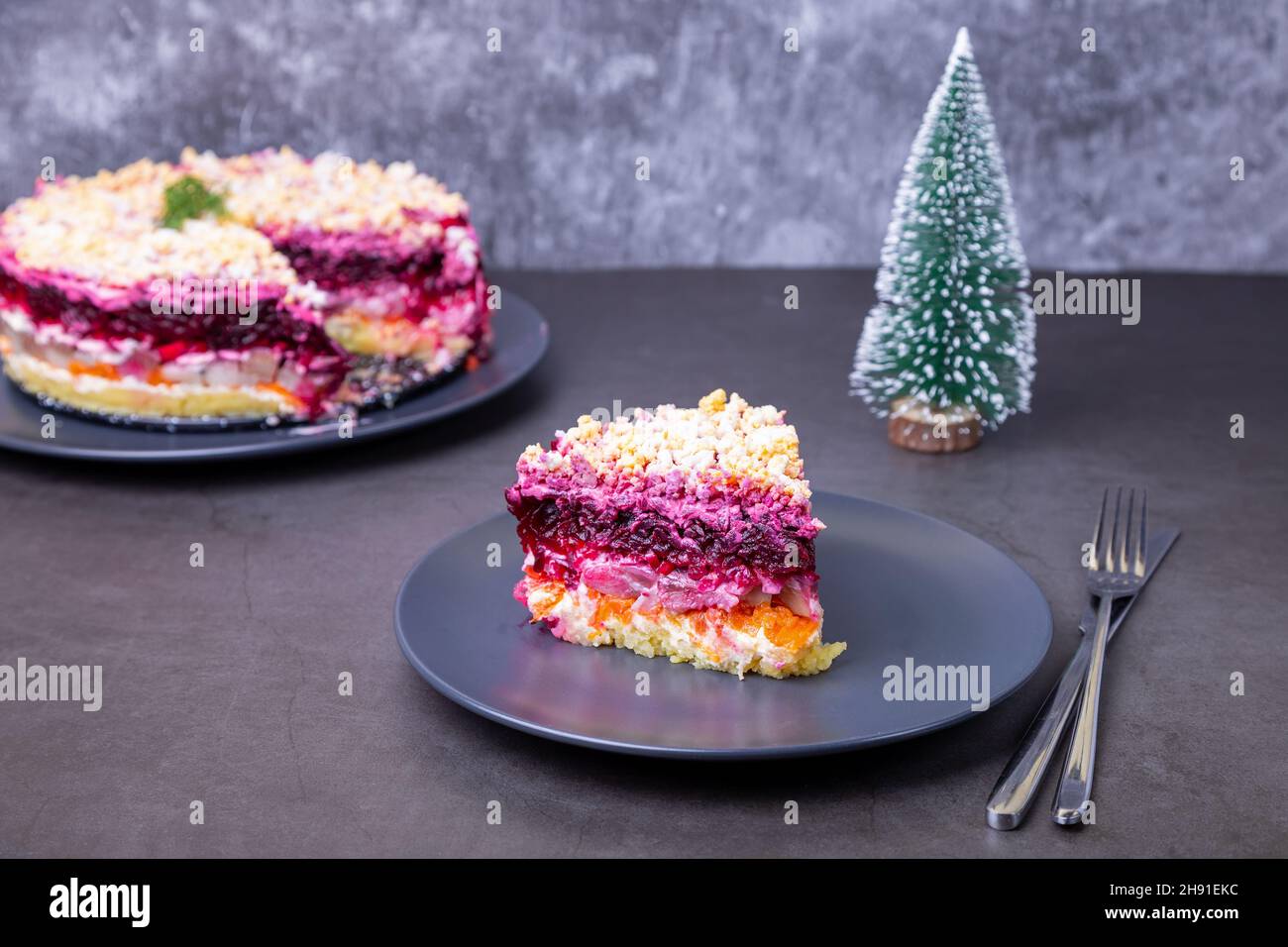 Salade de hareng sous un manteau de fourrure. Salade russe traditionnelle composée de plusieurs couches de hareng, de betteraves, de pommes de terre, de carottes et d'œufs. Petit arbre de Noël. Gros plan Banque D'Images