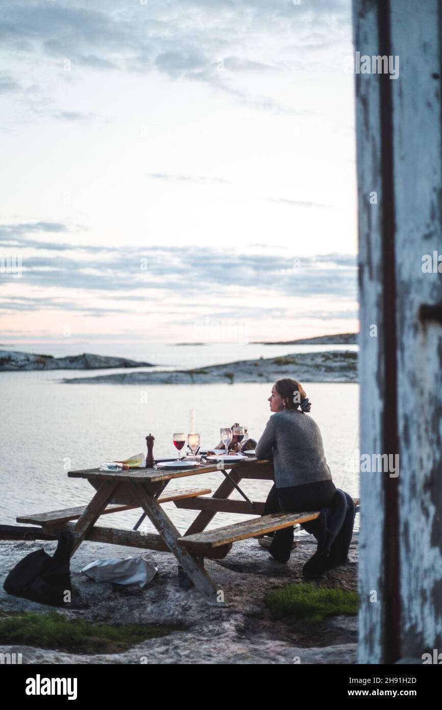 Femme ayant de la nourriture à table pendant le coucher du soleil Banque D'Images