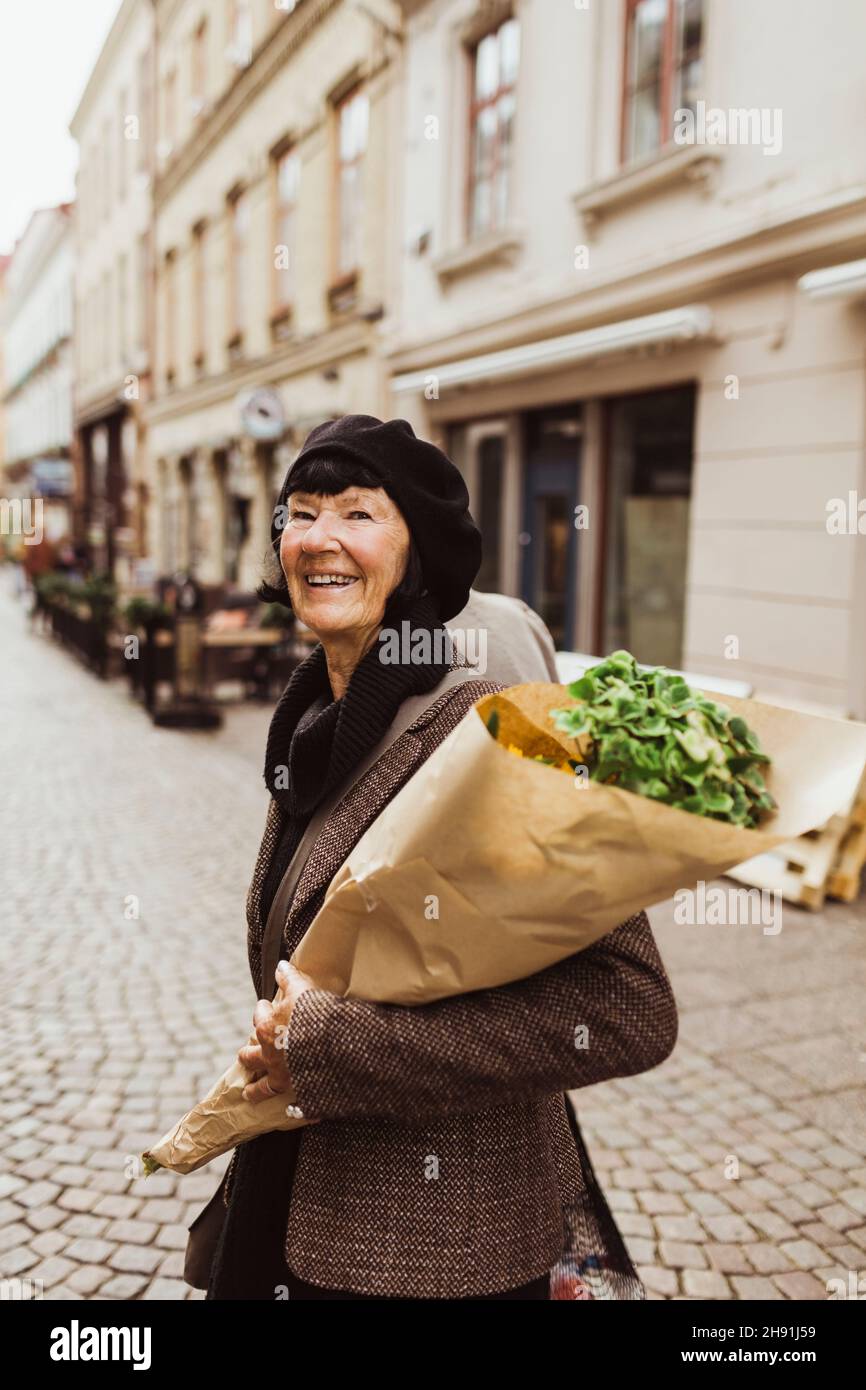 Femme âgée souriante avec bouquet dans la rue Banque D'Images