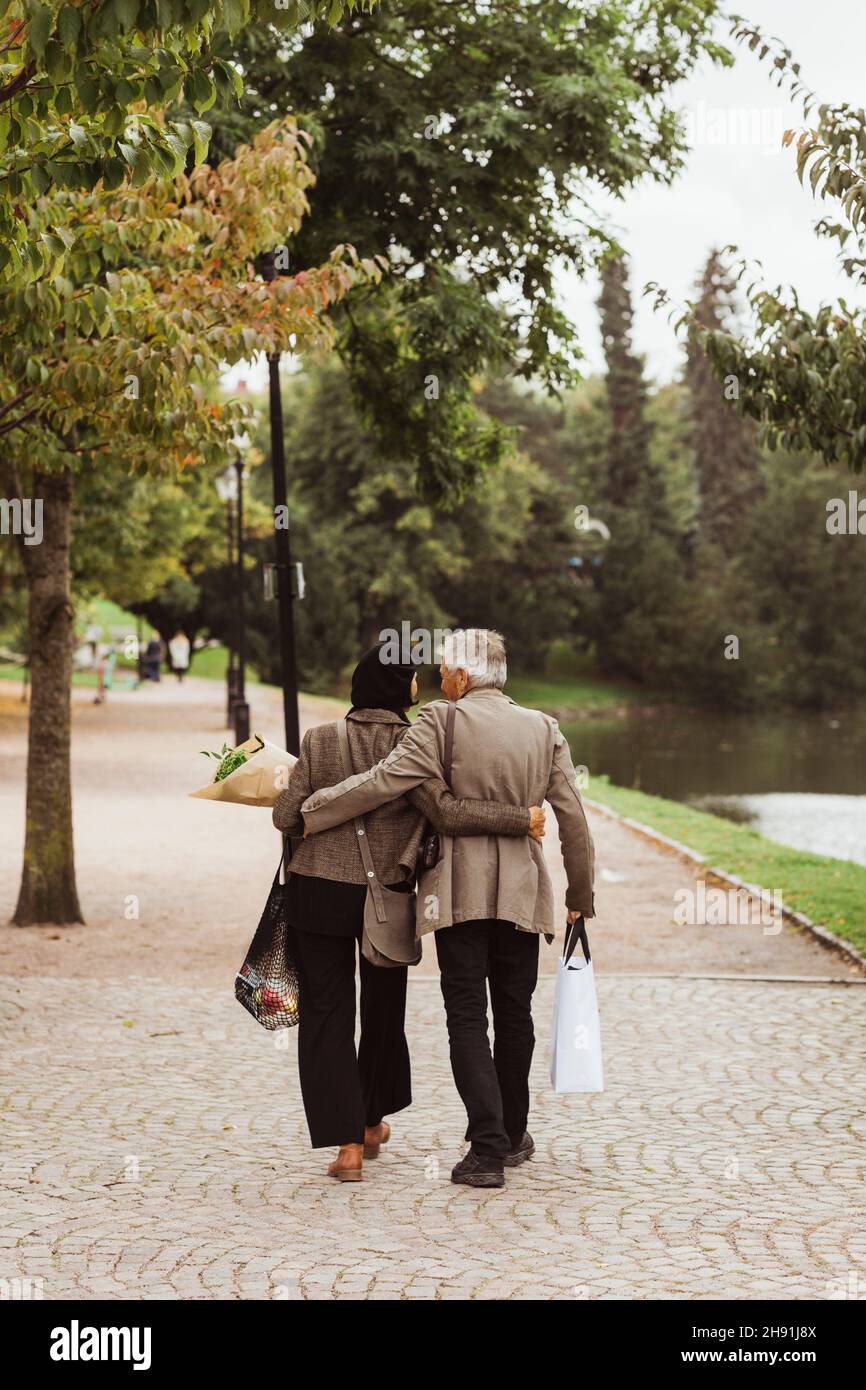 Vue arrière d'un couple senior marchant sur un sentier dans le parc Banque D'Images