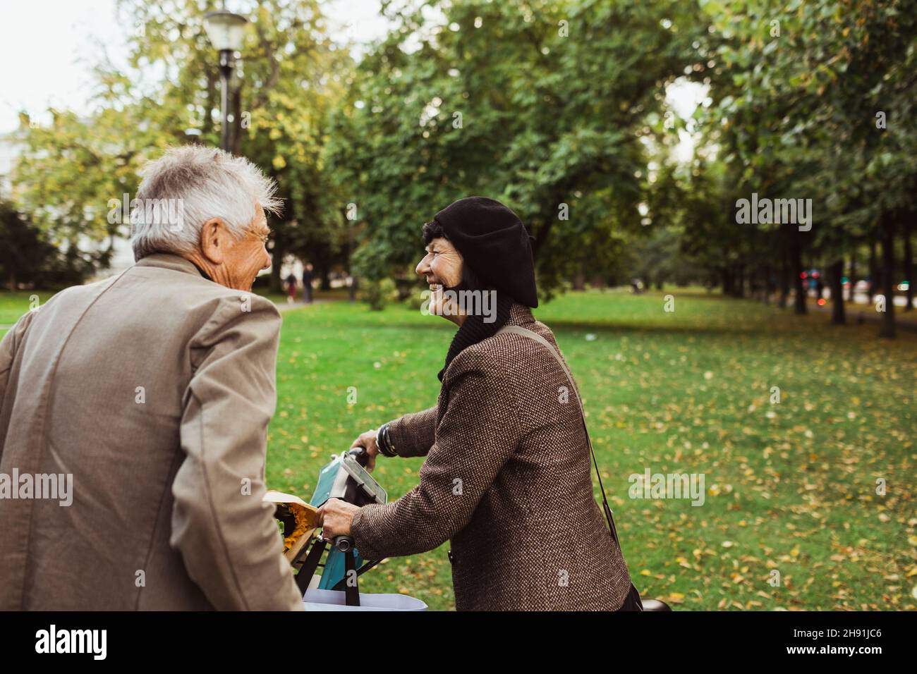 Couple de personnes âgées heureux passant du temps libre avec vélo électrique dans le parc Banque D'Images