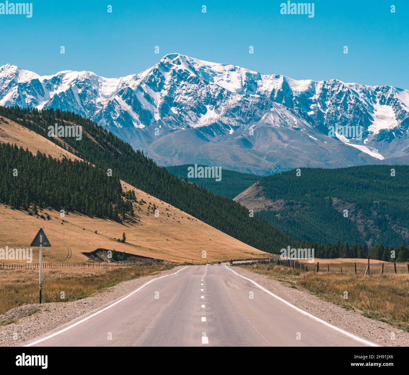 Route asphaltée vide devant d'immenses montagnes majestueuses avec des sommets enneigés.Magnifique paysage de la région de l'Altay, Russie. Banque D'Images