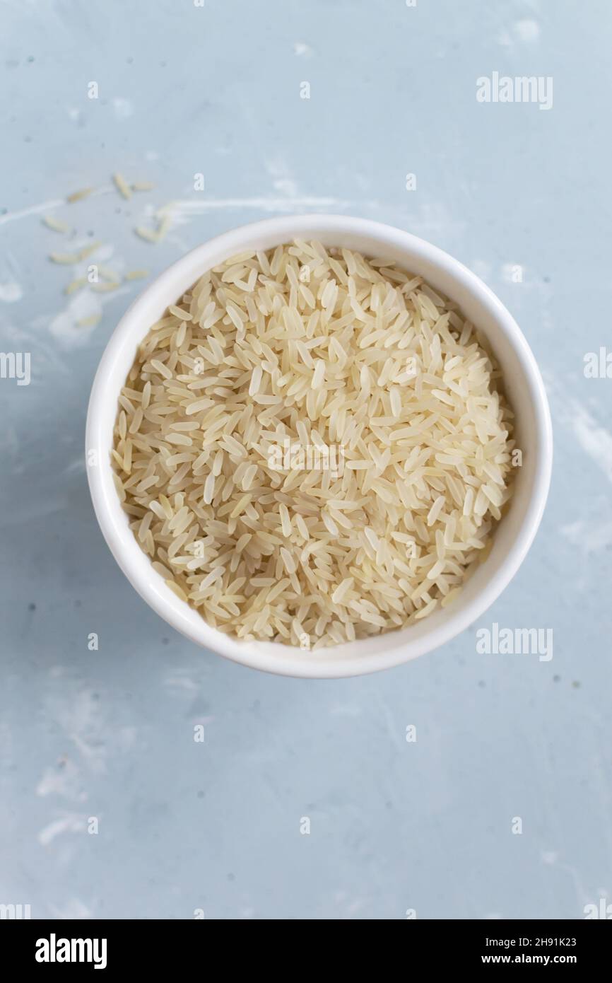 Riz blanc blanchi à grain long dans un bol blanc sur fond gris.Concept de cuisine végétarienne.Orientation verticale.Les plats de riz sont cuits dans tous les pays Banque D'Images