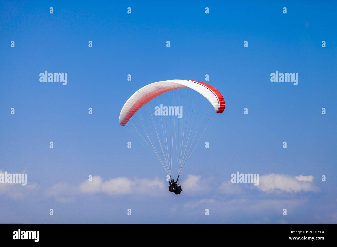 Un homme aventureux parapente contre le ciel bleu par une journée ensoleillée Banque D'Images