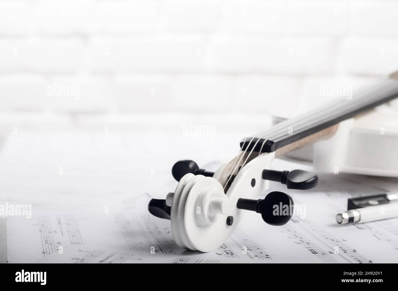Fermer la vue d'un violon et des notes de musique près de white brick wall Banque D'Images