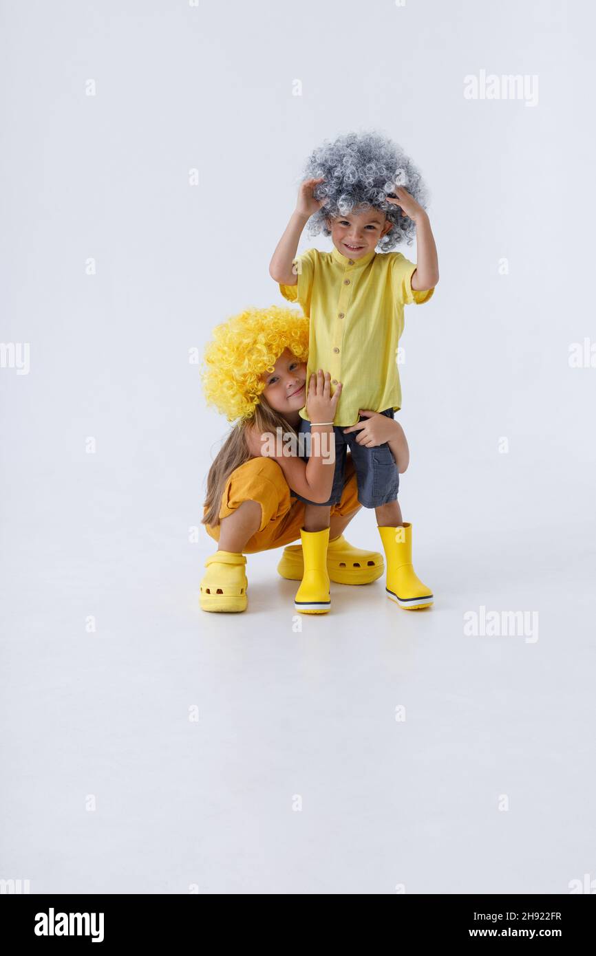 Enfants adorables dans des perruques qui se brandissent en studio Banque D'Images