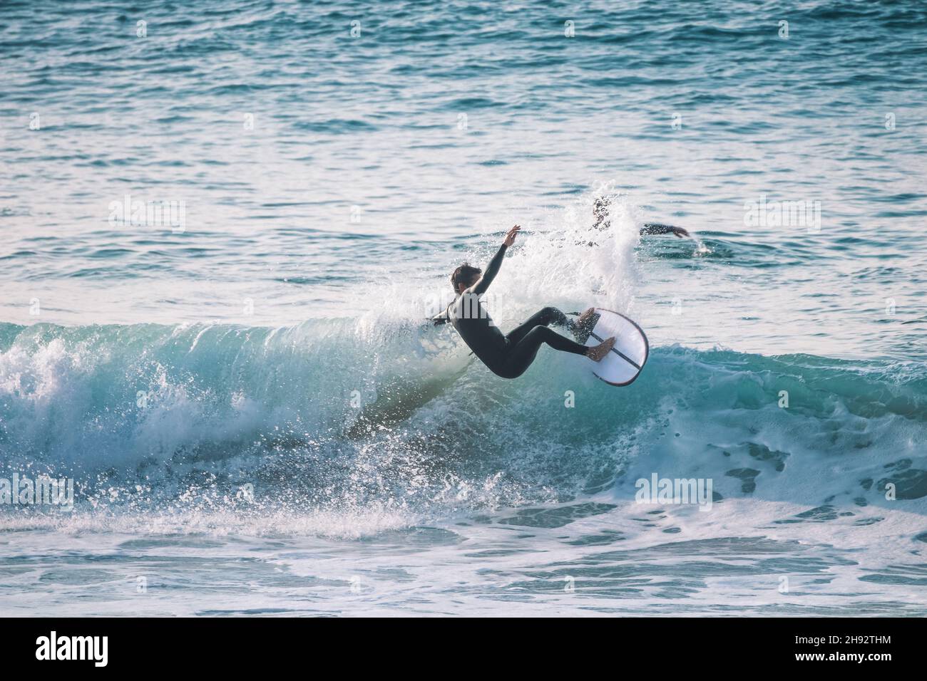 Surfer sur une vague bleue à un jour ensoleillé à Ericeira au Portugal. Banque D'Images