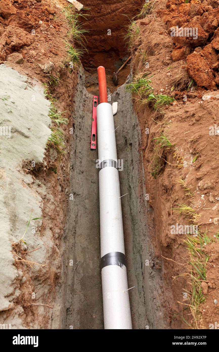 Pose de tuyaux d'égout pluvial souterrains dans un fossé. Installation de  la conduite d'eau principale et de l'égout sanitaire sur le chantier de  construction. Solutions de coffrage pour réinf Photo Stock 