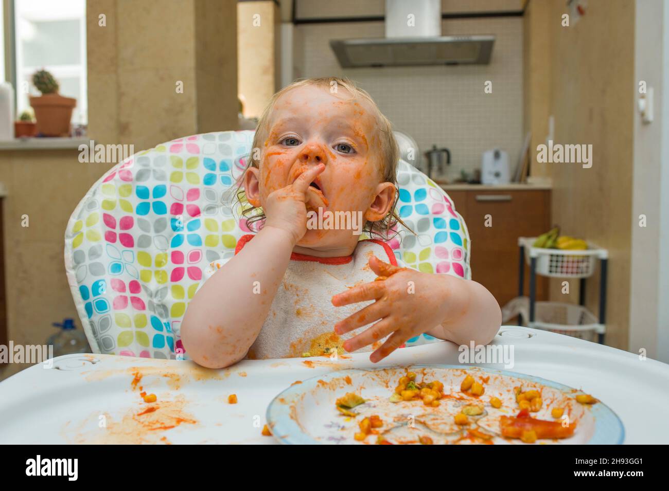 Une Petite Fille 15 Mois Mange Un Repas De Mais Doux Et De Sauce Tomate De Maniere Desordonnee Et Joue Avec Sa Nourriture Sur Une Chaise Haute Dans Sa Maison M M