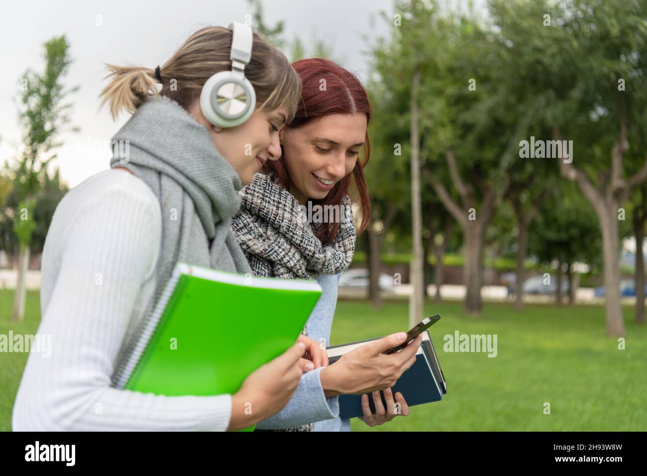 Deux jeunes filles regardent le téléphone cellulaire pendant qu'elles se promènent dans le parc Banque D'Images
