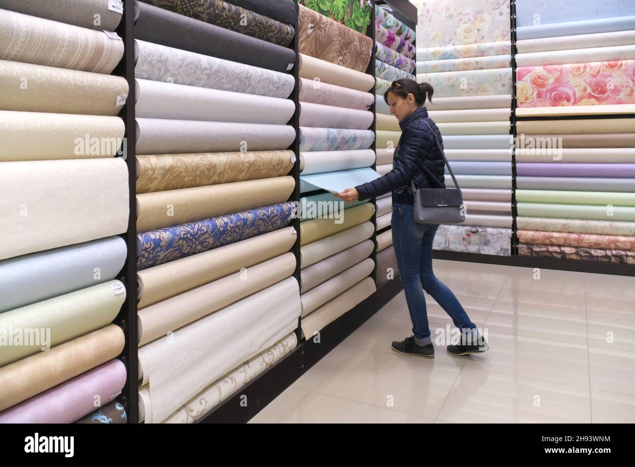 La fille choisit le papier peint dans le magasin. Banque D'Images