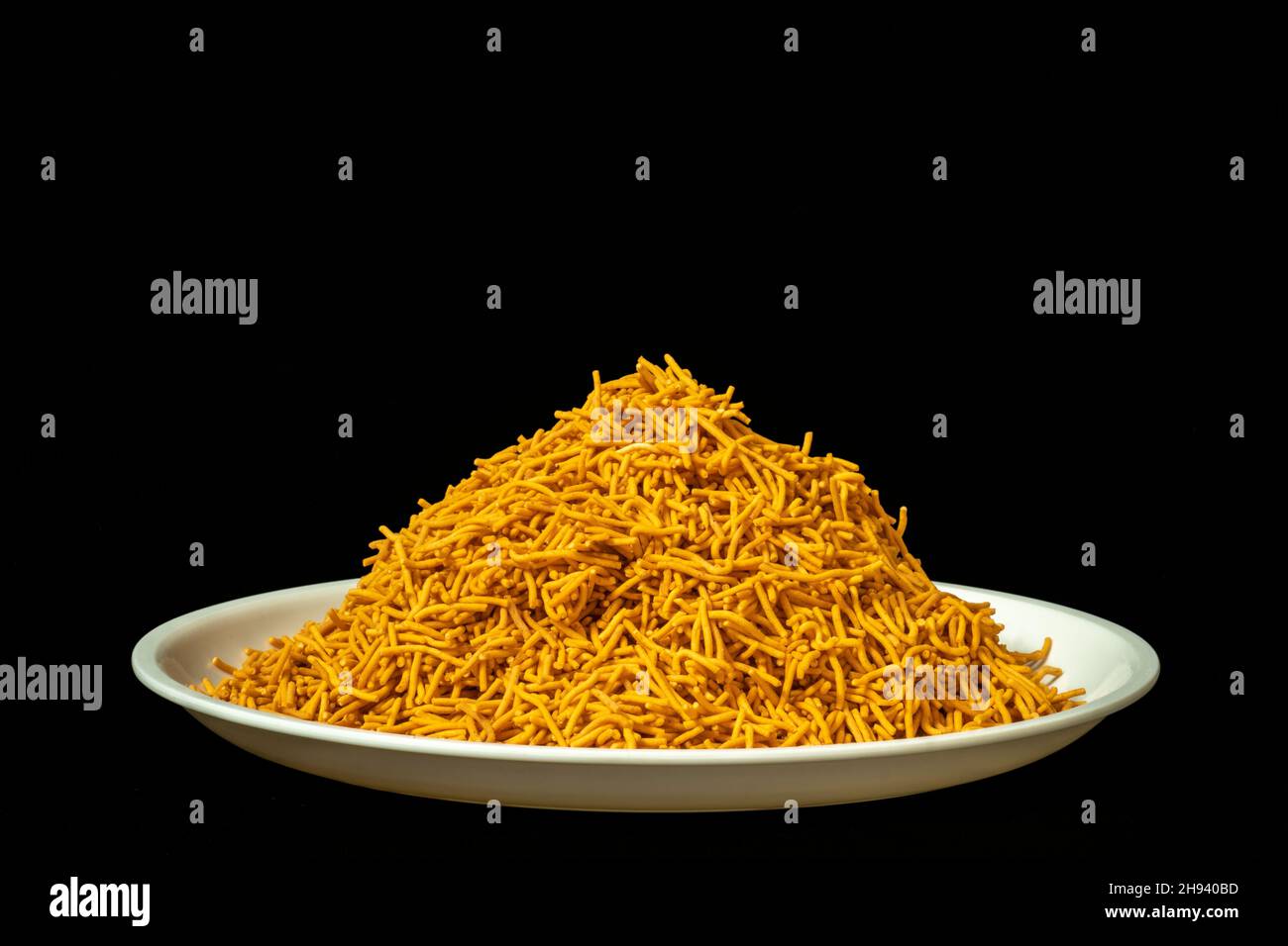 Tas de Spicy Sev Namkeen Food dans un plat blanc, farine de pois chiches et épices, isolé dans un fond noir Banque D'Images