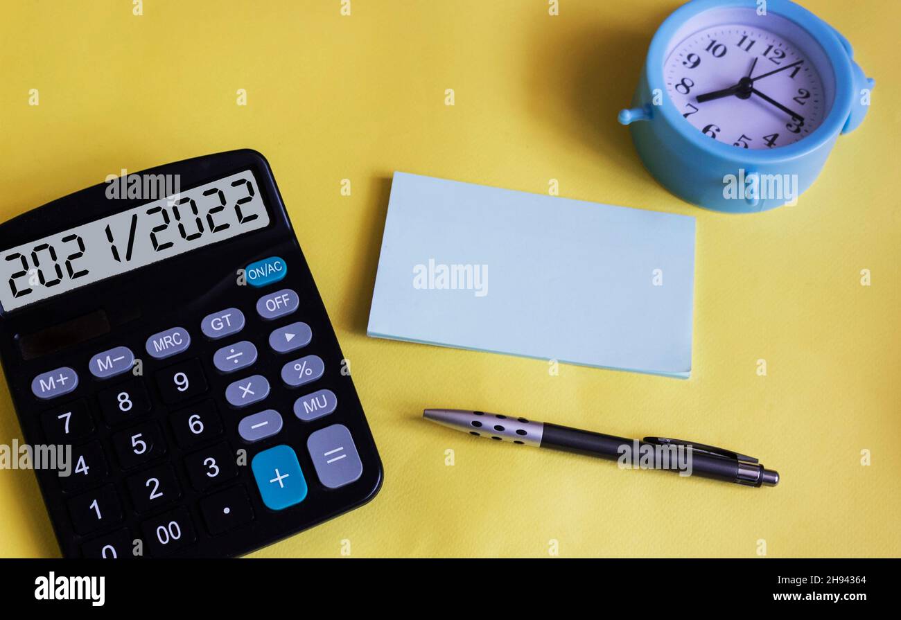 Le texte 2021 2022 sur l'affichage d'une calculatrice.Sur fond jaune, une horloge, un stylo et un bloc-notes pour écrire.Planification de la nouvelle année Banque D'Images