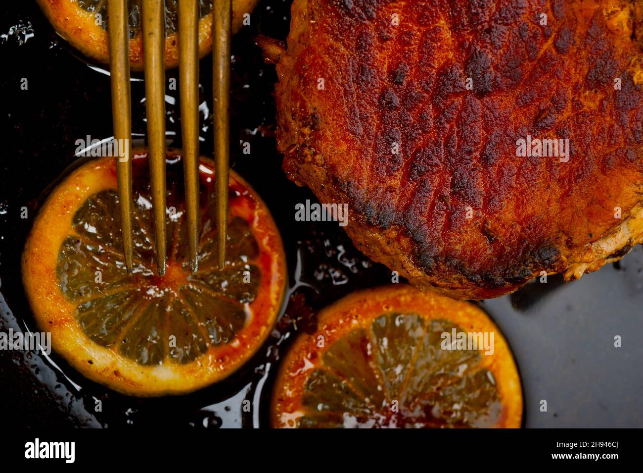 Côte de porc grillé sur iron skillet avec le citron et l'assaisonnement épices Banque D'Images