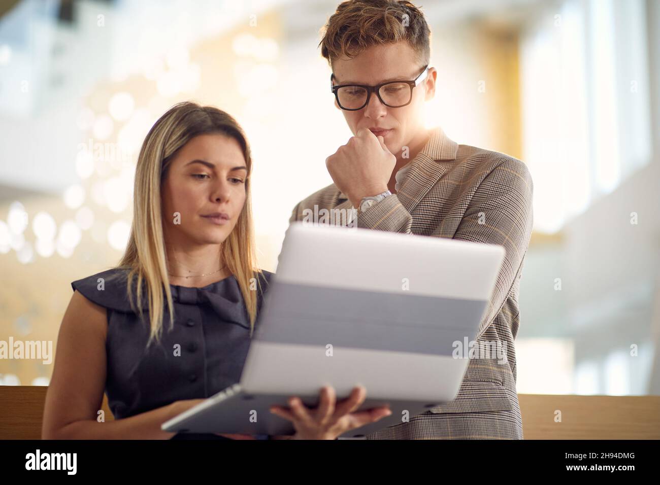 Une jeune femme d'affaires et son jeune collègue masculin se tenant dans le couloir et regardant un contenu d'ordinateur portable dans une atmosphère agréable.Affaires, personnes, c Banque D'Images