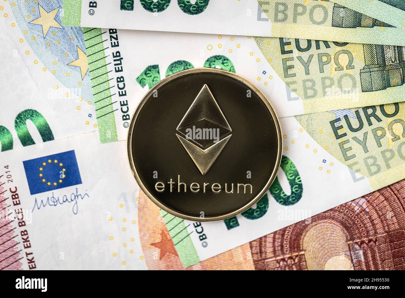 Pièce de monnaie physique Ethereum qui s'élève au-dessus des factures de 100 euros. Banque D'Images