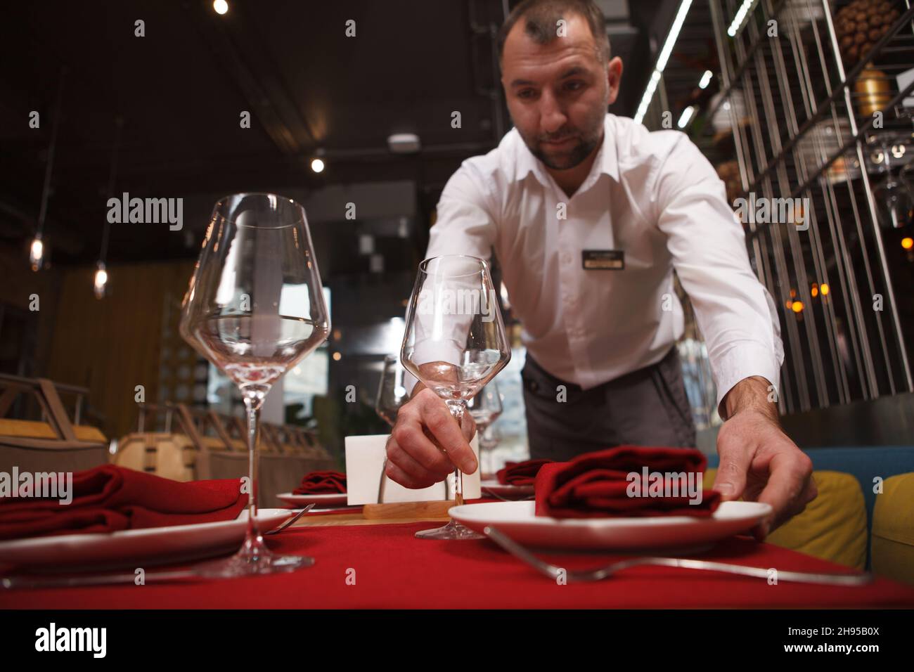 Un serveur professionnel met des assiettes sur les tables du restaurant Banque D'Images