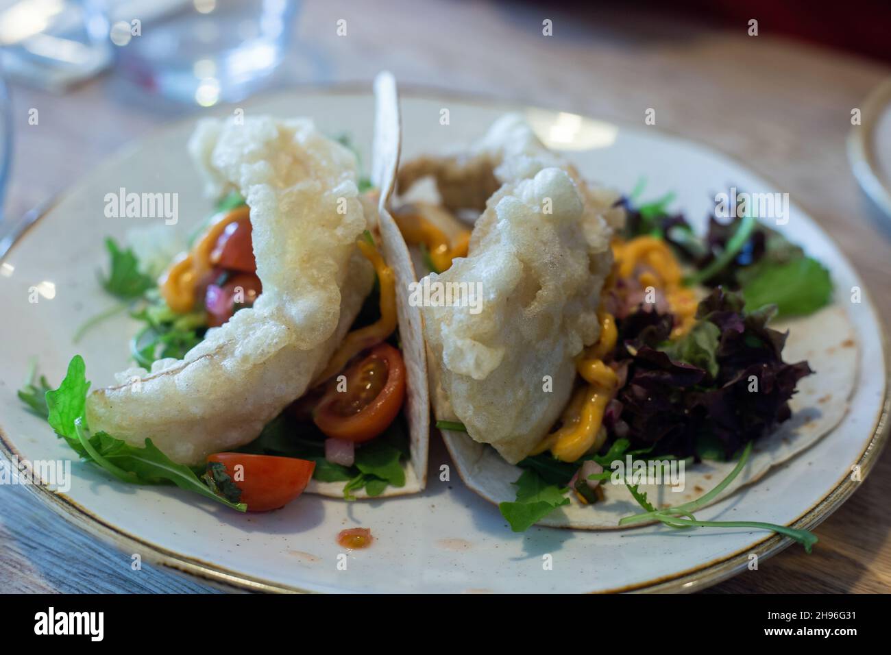 Délicieux tacos de poisson servis sur une assiette blanche avec garnitures de salade. Banque D'Images
