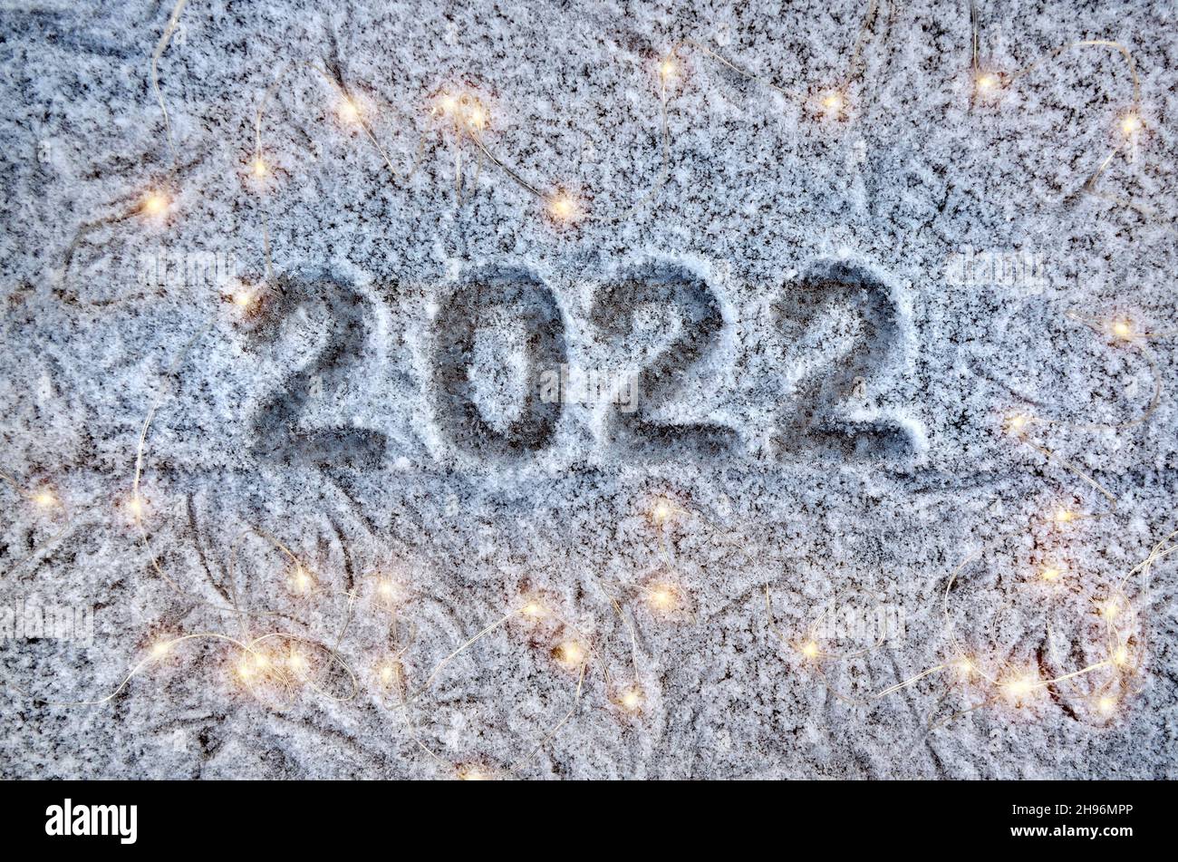 Inscription 2022 sur une surface enneigée avec des lumières de noël.Concept de la nouvelle année 2022. Banque D'Images