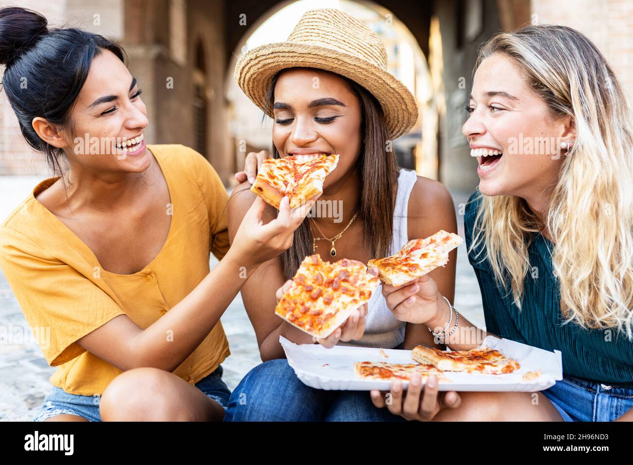 Trois gaies multiraciales femmes de manger de la pizza dans la rue Banque D'Images