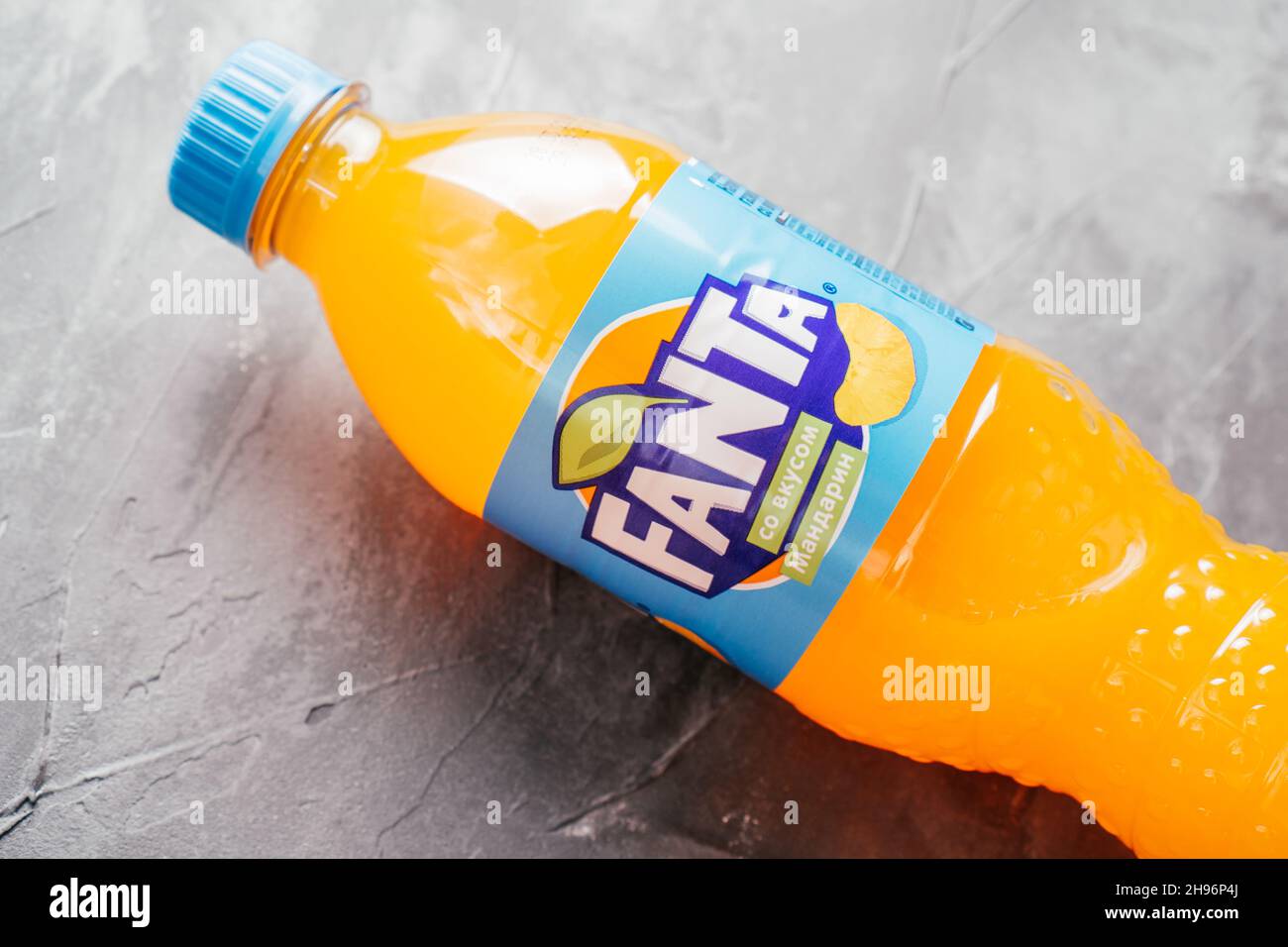 La bouteille en plastique transparent de Fanta se trouve sur une surface en béton gris.Bouteille avec boisson à l'orange et étiquette bleue au goût de mandarine en russe Banque D'Images