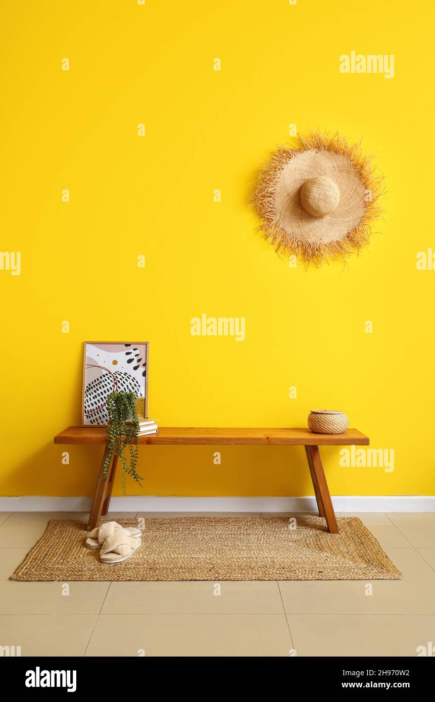 Banc en bois avec photo, livres et maison près du mur jaune Banque D'Images