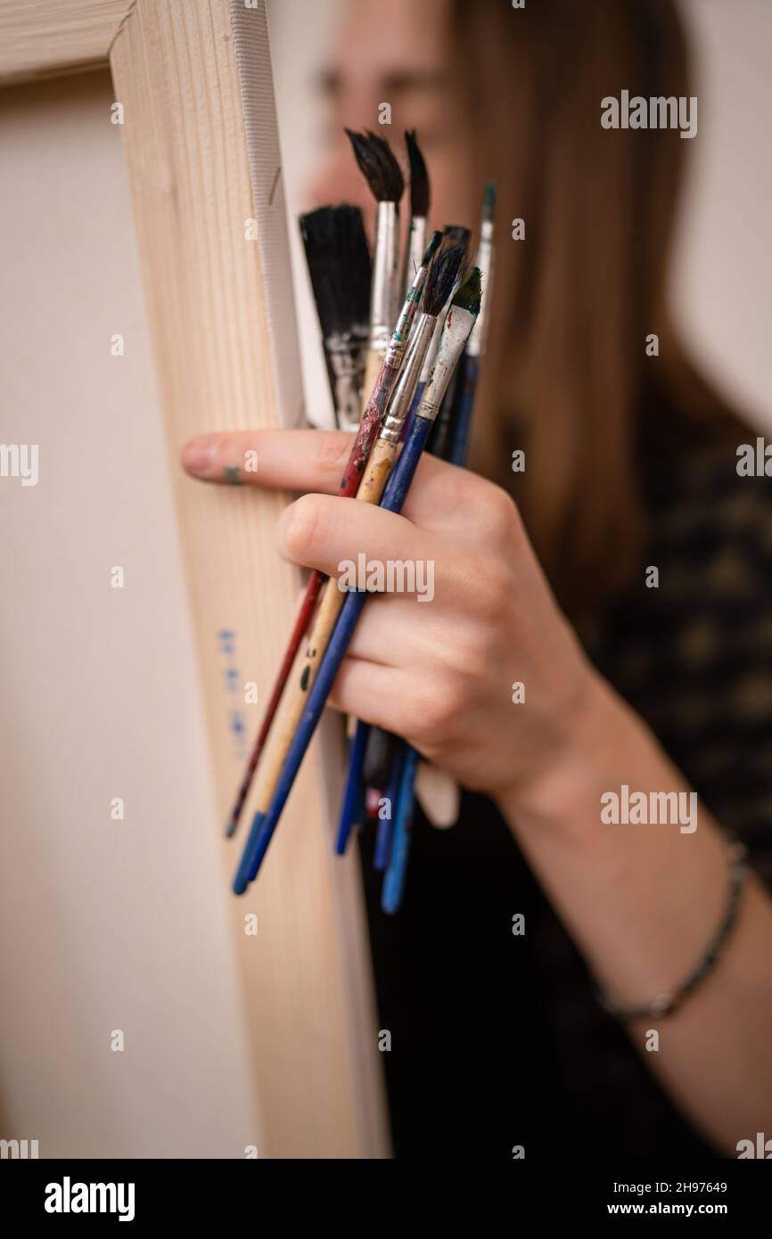Une jeune femme caucasienne artiste professionnelle ou étudiante peintre amateur peinture à la maison tenant des pinceaux à la main posant avec l'espace de copie c Banque D'Images
