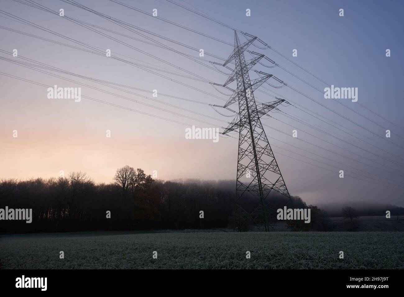 Pylône d'électricité torqué (Strommasten) également pylône de ligne aérienne dans le matin d'hiver brumeux.Vue latérale.Paysage. Banque D'Images